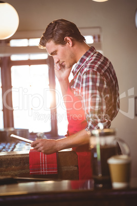 Waiter talking on mobile phone while using digital tablet