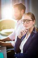 Businesswoman looking at camera while her colleague working in t