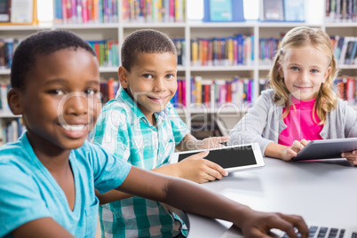 Kids using laptop and digital tablet in library