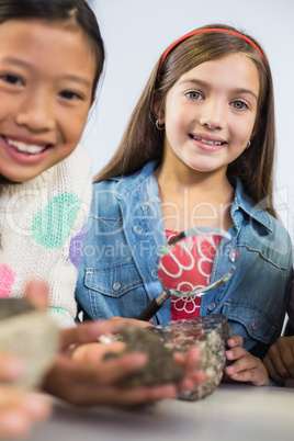 Portrait of kids holding magnifying glass in classroom