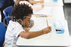School boy doing homework in classroom