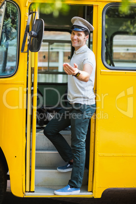 Bus driver standing at the entrance of bus and gesturing