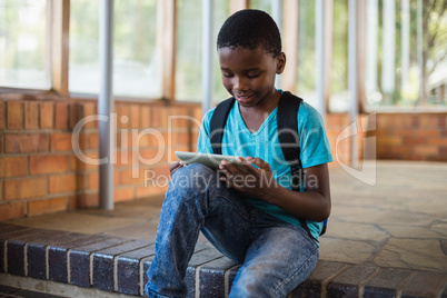 Schoolboy sitting on staircase using digital tablet