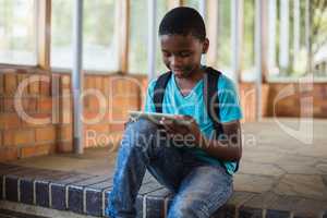 Schoolboy sitting on staircase using digital tablet
