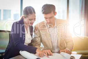 Businessman and businesswoman discussing blueprint