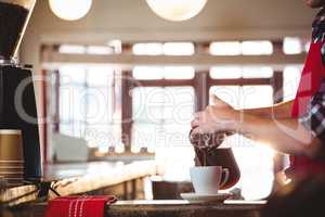 Mid section of waiter pouring a cup of coffee