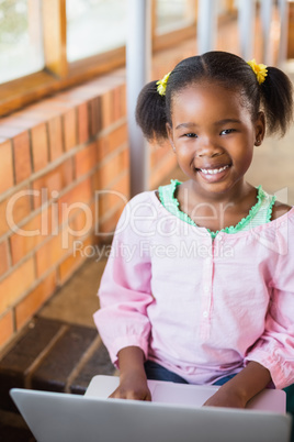 Schoolgirl sitting on stairs and using laptop