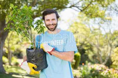 Portrait of volunteer man holding plant