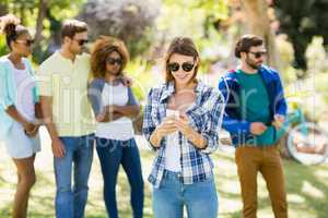 Woman using mobile phone with friends in background