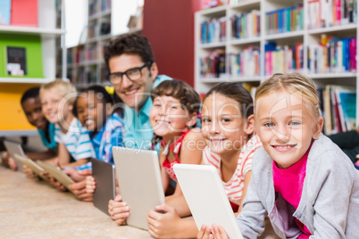 Teacher and kids using digital tablet in library