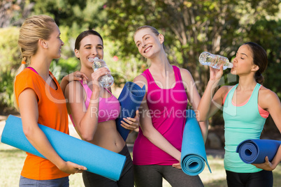 Beautiful women holding exercise-mat in park