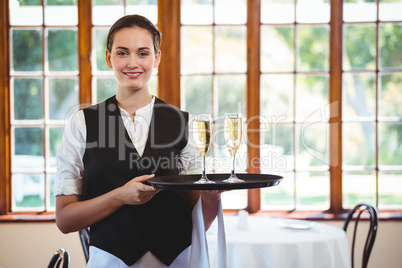 Portrait of waitress holding serving tray with champagne flutes&