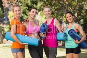 Beautiful women holding exercise-mat in park