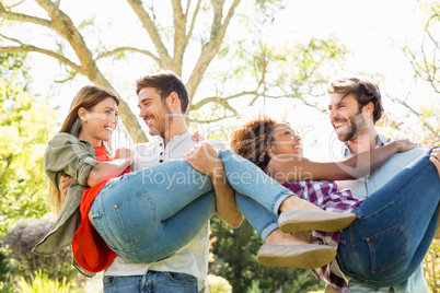 Man giving piggyback to woman while having glass of beer