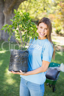 Portrait of volunteer woman holding plant