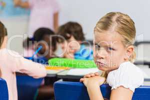 Portrait of sad schoolgirl sitting in the classroom