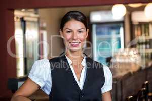 Portrait of waitress standing at bar counter