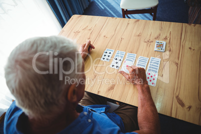 Senior man playing cards on a table