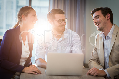 Businessmen and businesswoman interacting using laptop