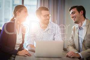 Businessmen and businesswoman interacting using laptop
