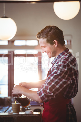 Smiling waiter pouring a cup of coffee