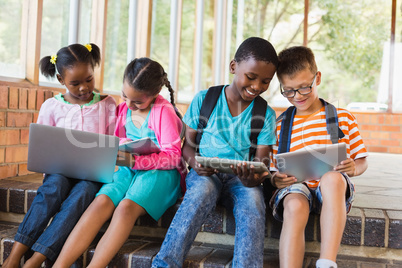 Kids sitting on staircase using laptop and digital tablet