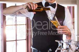 Mid section of bartender pouring a beer in a glass