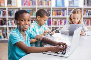 Kids using laptop and digital tablet in library