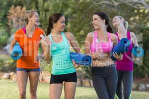 Beautiful women holding exercise-mat in park