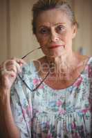 Smiling senior woman raising glasses to her head