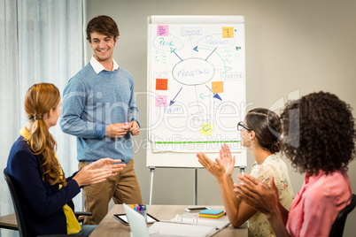 Coworkers applauding a colleague after presentation Coworkers applauding a colleague after presentation