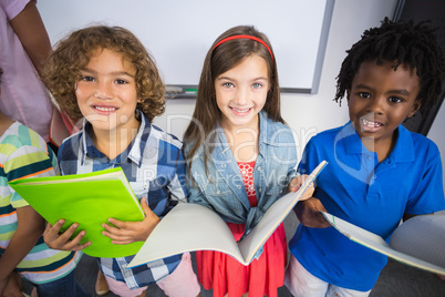 Portrait of kids holding book in classroom