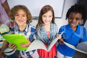 Portrait of kids holding book in classroom