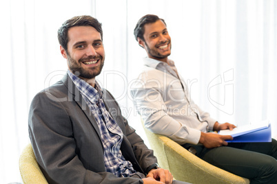 Men smiling at camera while sitting in the office