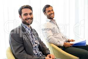 Men smiling at camera while sitting in the office