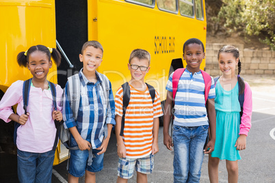 Smiling kids standing together in front of school bus