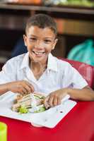 Portrait of schoolboy having lunch during break time