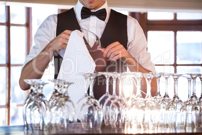 Mid section of bartender cleaning wineglass