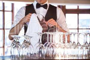 Mid section of bartender cleaning wineglass