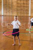 Schoolgirl playing with hula hoop in school gym