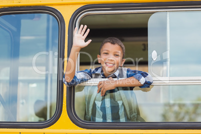 Portrait of schoolboy waving hand from bus