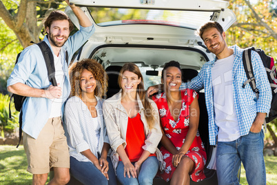 Group of friends on trip sitting in trunk of car