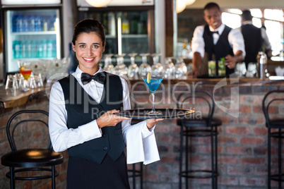 Portrait of bartender holding serving tray with glass of cocktai