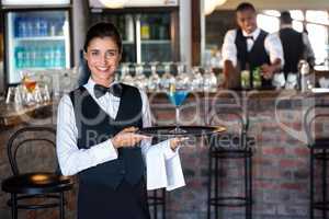 Portrait of bartender holding serving tray with glass of cocktai