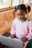 Schoolgirl sitting on stairs and using laptop