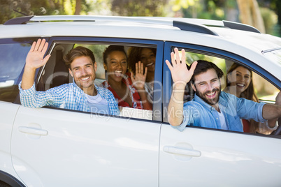 Group of friends waving hands from car