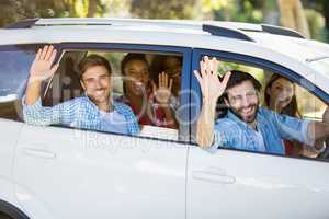 Group of friends waving hands from car
