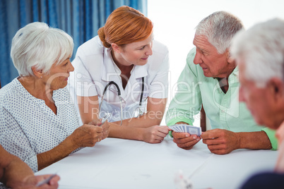 Smiling nurse looking at senior person during a game of cards