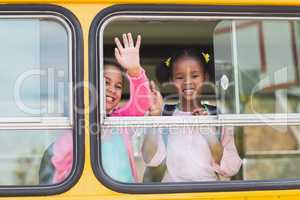 Portrait of school kids waving hand from bus