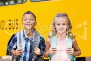 Smiling kids standing in front of school bus